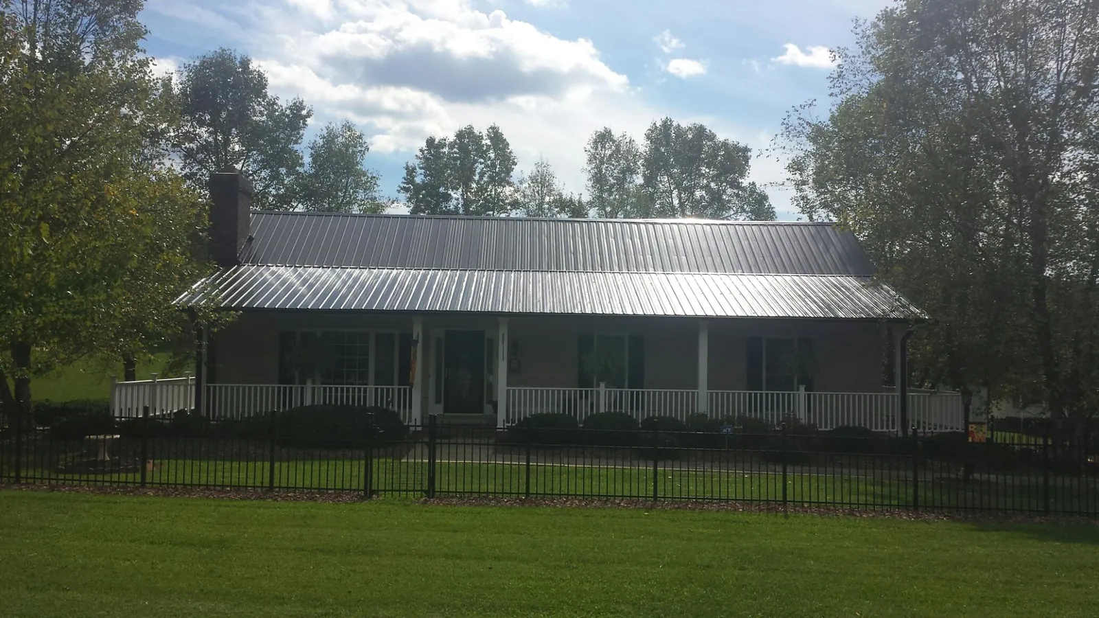 Gray metal roof on a brick ranch with a full width front porch in Unionville